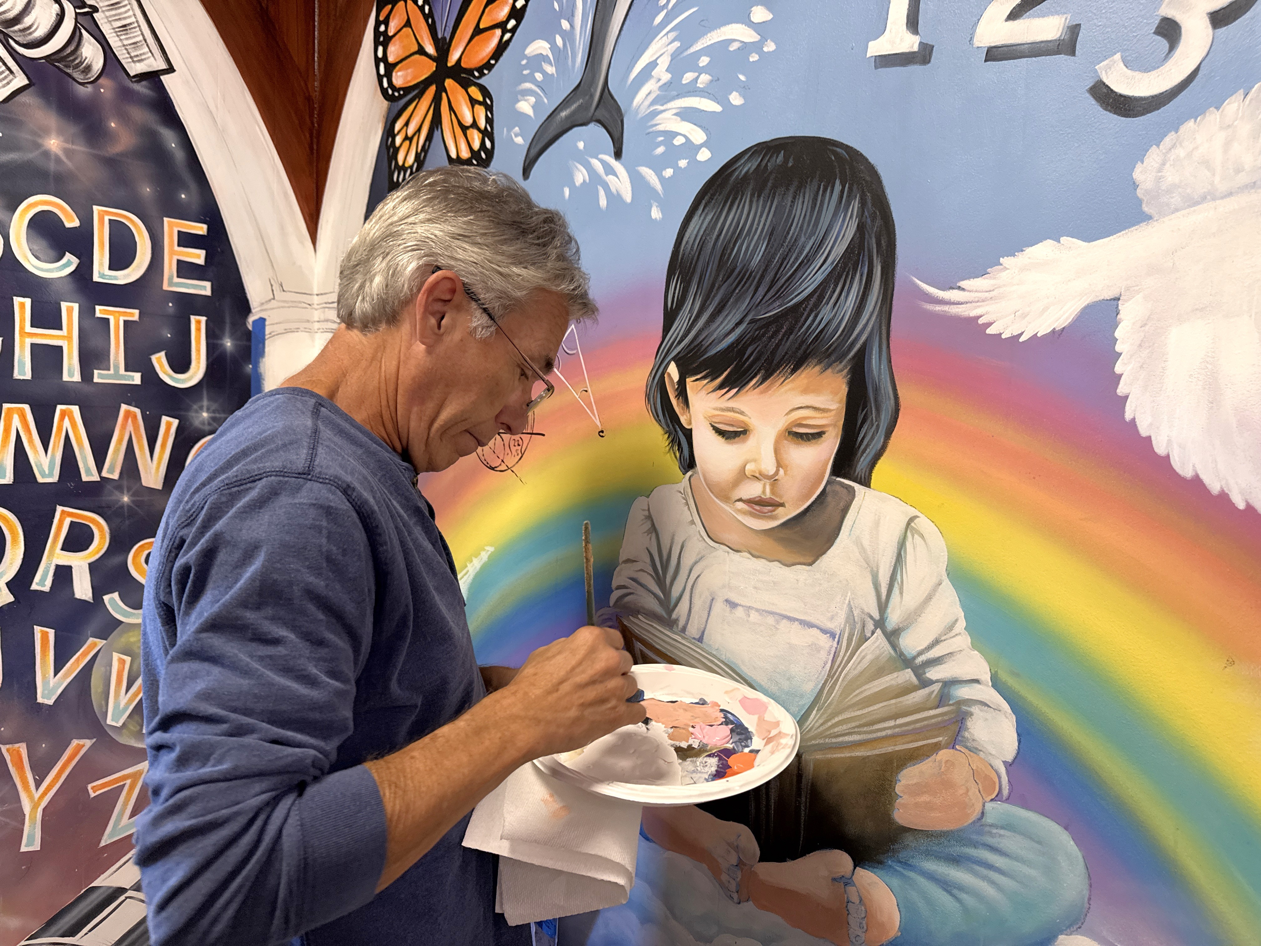 Muralist working on artwork in front foyer 